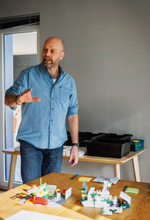 Philipp Tessin erklärt an einem Tisch mit LEGO®-Modellen